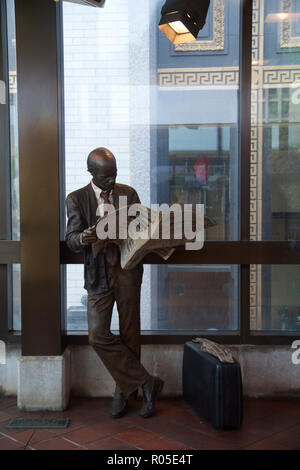 DETROIT, Michigan, Vereinigte Staaten - 22. Mai, 2018: eine Statue eines Mannes eine Zeitung lesen auf einer Plattform der Detroit People Mover Straßenbahn Stockfoto