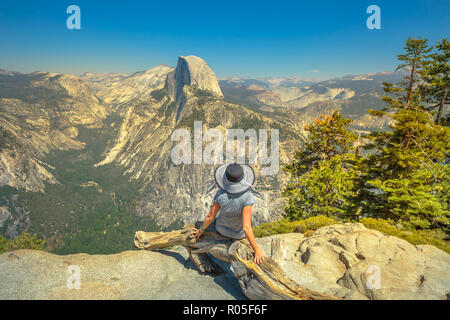 Junge Frau sitzend, Glacier Point in Yosemite National Park. Müde Wanderer, entspannen im beliebten Half Dome vom Glacier Point übersehen. Sommer reisen urlaub Konzept. Kalifornien, USA Stockfoto