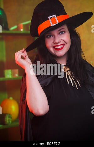 Foto von smiling witch in hat an dunklen Zimmer Stockfoto