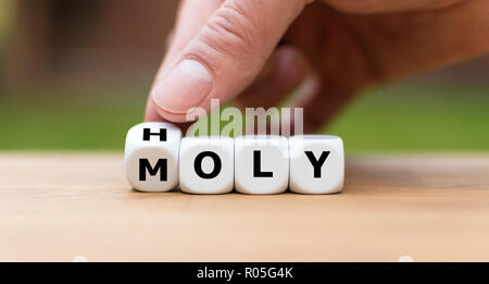 Hand dreht einen Würfel und Änderungen das Wort "heilig" zu Oly 'm' Stockfoto