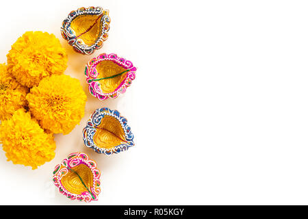 Happy Diwali - Ton Diya Lampen leuchten bei Dipavali, hinduistische Lichterfest feiern. Bunte traditionelle Öllampe diya mit gelben Blumen auf whi Stockfoto