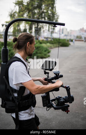 Professionelle Videofilmer holding Kamera auf 3-Achs Gimbal, die auf einfache Rig montiert. Videofilmer mit Steadicam. Pro Ausrüstung hilft Video in hoher Qualität ohne Schütteln zu machen. Stockfoto