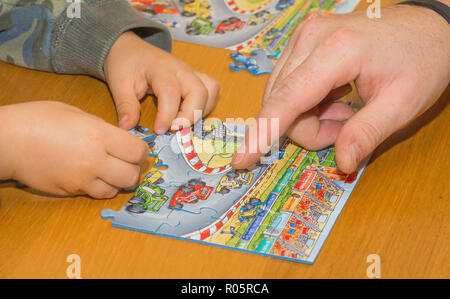 Kleines Kind mit Puzzles auf hölzernen Tisch spielen zusammen mit Eltern, Lifestyle Menschen Konzept Stockfoto