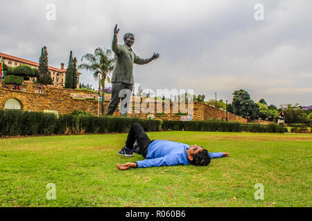 Eine Indische asiatische junge männliche, rest vor Nelson Mandela Statue in Pretoria in der Nähe der Parlamentsgebäude und Union Buildings Stockfoto