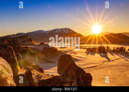 Die Sonne über die Berge und wirft einen goldenen Glanz über den felsigen Tal Stockfoto