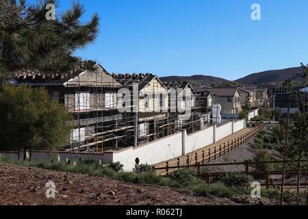 Vier neue Familie Häuser im Bau und Gerüstbau in einem vorstädtischen Viertel mit öffentlichen Wanderwegen, Fechten, Kopie Platz im blauen Himmel umgeben Stockfoto