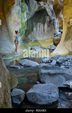 Nach kaukasischen Frauen stehen durch den Stream im Tunnel. National Park Ukhahlamba Drakensberg, Kwazulu Natal Provinz, Südafrika Stockfoto