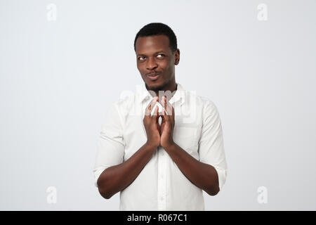 Gerissen tricky afrikanischen Jungen Mann denken Suchen beiseite mit der Hand am Kinn Stockfoto