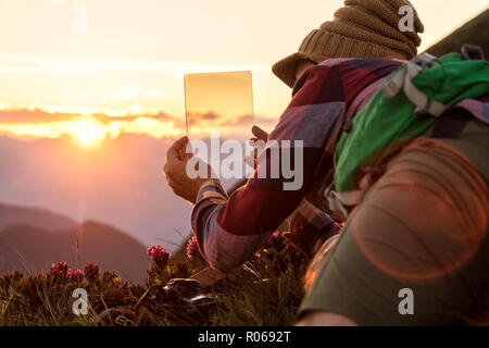 Mann bei Sonnenuntergang mit abgestuften Fotografie Filter in seiner Hand, San Marco Pass, Bergamasker Alpen, Provinz Bergamo, Lombardei, Italien, Europa Stockfoto