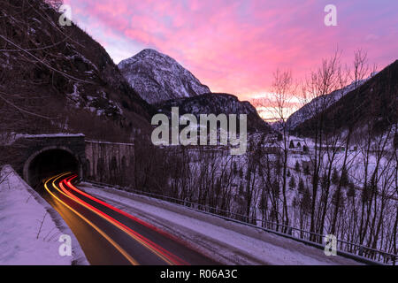 Auto trail Leuchten auf der vereisten Straße im Morgengrauen, Campodolcino, Spluga Tal, Provinz Sondrio, Valtellina, Lombardei, Italien, Europa Stockfoto