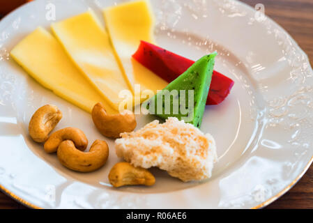 Scheiben von bunten Käse und Muttern an der Platte Stockfoto