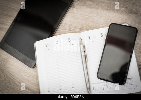 Leeres Notizbuch mit Stift und Smartphone auf Holztisch, Business Konzept Stockfoto