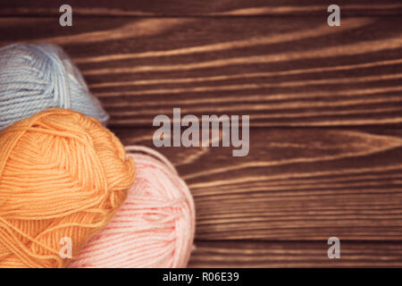 Ansicht von oben in Blau und Rosa Gelb wolle Kugeln der Thread auf hölzernen stricken Hintergrund. Stockfoto