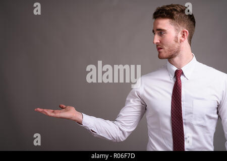Porträt der jungen Hübschen Geschäftsmann gegen grauer Hintergrund Stockfoto
