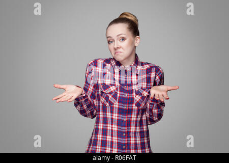 Ich weiß nicht. Verwirrt schöne Mädchen mit rosa kariertem Hemd, sammelte bun Frisur und Make-up-ständigen und Wegsehen mit Fragwürdigem Gesicht. die Pflege von Stockfoto