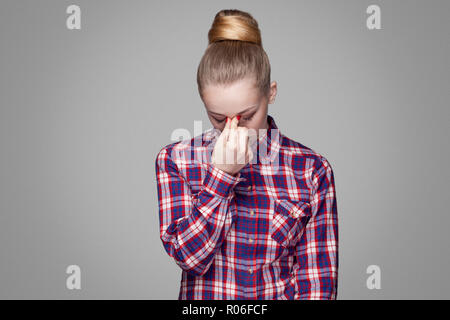 Traurig, müde oder schönen blonden Mädchen in Rot, Rosa kariertem Hemd niedergedrückt, sammelte bun Frisur, Make-up und halten Kopf und Schreien. Stockfoto