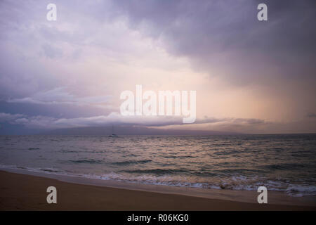 Sonnenuntergang Marine bei bewölktem Himmel als Sturm Ansätze Insel mit Gold Grau Rosa und Lila Farben reflektieren in rauer See Oberfläche Stockfoto