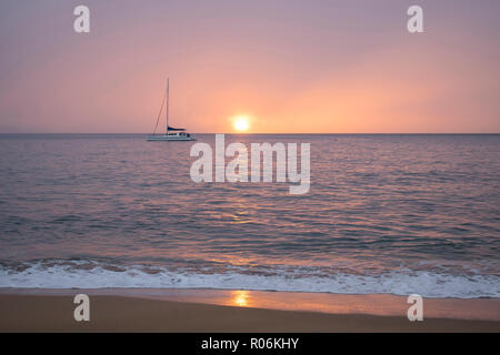 Gedämpften rosa Sonnenuntergang Meereslandschaft mit Boot und Sonne am Horizont und Reflektierende am Ocean Oberfläche Stockfoto