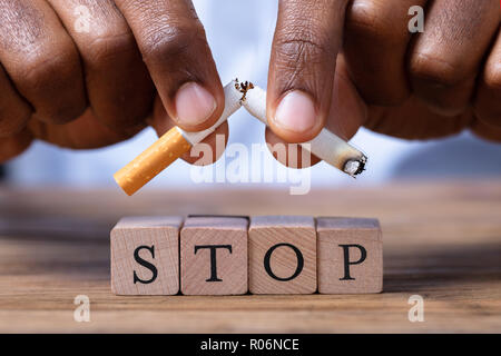 Nahaufnahme einer Hand, die Zigarette über Holz- Anschlagblöcke Stockfoto