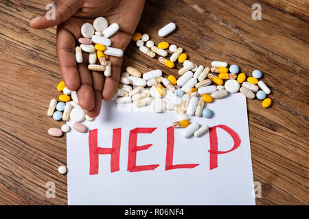 Erhöhten Blick in eines Mannes Hand Pillen mit Hilfe Text auf Papier Stockfoto