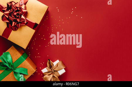 Haufen Geschenkboxen und Sterne Konfetti auf rotem Hintergrund. Flach Komposition für Weihnachten mit kopieren. Stockfoto