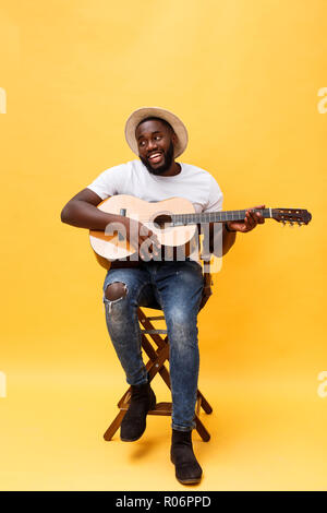 In voller Länge Foto von Angeregten künstlerische Mann, der seine Gitarre spielen. Auf gelben Hintergrund. Stockfoto