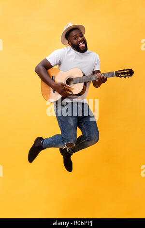 In voller Länge Foto von Angeregten künstlerische Mann, der seine Gitarre spielen. Auf gelben Hintergrund. Stockfoto
