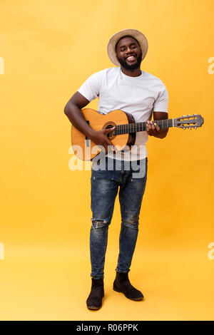 In voller Länge Foto von Angeregten künstlerische Mann, der seine Gitarre spielen. Auf gelben Hintergrund. Stockfoto