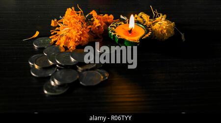 Isolierte lit diya, Blumen und Münze platziert auf einem Tisch Stockfoto