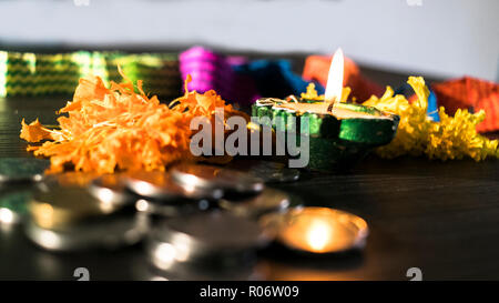 Isolierte lit diya, Blumen und Münze platziert auf einem Tisch Stockfoto