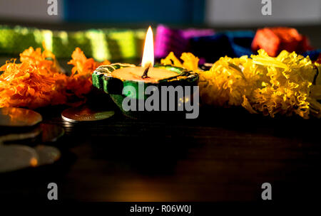 Isolierte lit diya, Blumen und Münze platziert auf einem Tisch Stockfoto