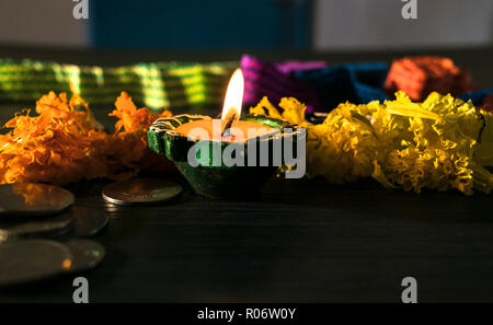 Isolierte lit diya, Blumen und Münze platziert auf einem Tisch Stockfoto