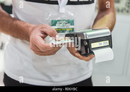 Kaukasische Verkäufer Mann hält Karte Maschine oder POS-Terminal in seinen Händen. Bezahlung mit der NFC-Technologie auf Kontaktlose Kreditkarte. Stockfoto