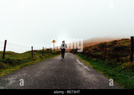 Junge Frau auf Hoodie allein auf misty Straße. Stockfoto