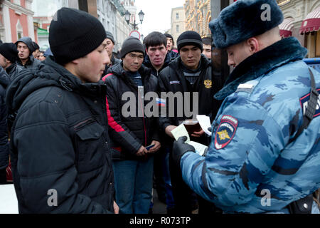 Ein Polizist prüft Dokumente von Arbeitsmigranten aus Zentralasien während der Eingabe auf dem Roten Platz in Moskau, Russland Stockfoto