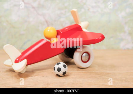 Miniatur Fußball zu einem spielflugzeug liegen auf einem Holztisch auf einem Hintergrund Karte Stockfoto