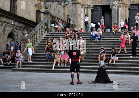 Ein Jongleur tritt vor dem Dom auf. Plaza de Platerias, Menschen auf der Treppe, Sommerfest. Santiago de Compostela, Spanien. August 2018. Stockfoto