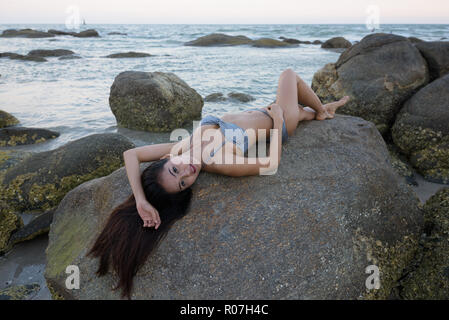 Junge schöne asiatische Frau liegend und auf den Felsen o Posing Stockfoto