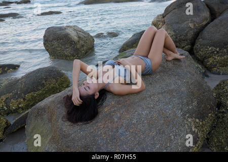 Junge schöne asiatische Frau liegend, während mit den Augen posing cl Stockfoto