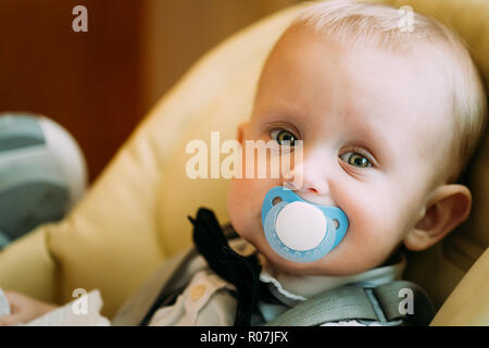 Pretty Baby Boy mit großen grünen Augen sitzen gelbe mit Schnuller Stockfoto