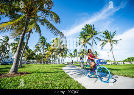 MIAMI - ca. September 2018: Touristen schlendern und Zyklus direkt an der Strandpromenade am Ocean Drive in South Beach. Stockfoto