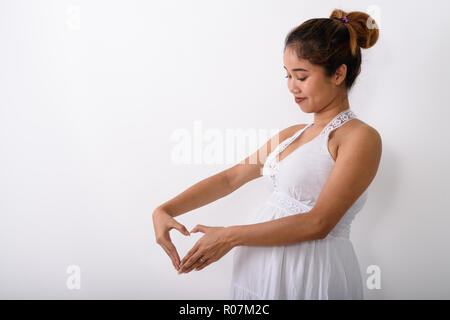 Profil anzeigen von jungen asiatischen schwangere Frau, Herz hand sig Stockfoto