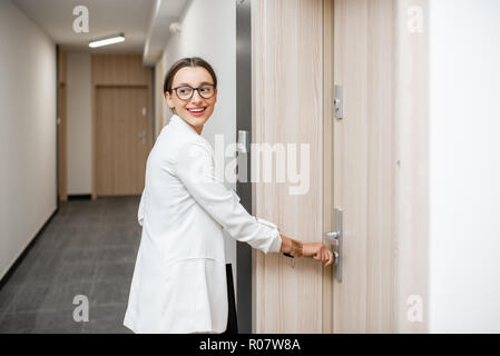 Junge Geschäftsfrau Öffnen der Wohnungstür mit Schlüssel stehend im Flur des modernes Wohnhaus Stockfoto
