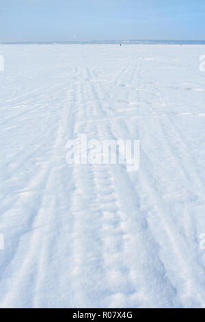 Spuren von Schlitten und Ski auf weißen frisch gefallenen Schnee im Winter zugefrorenen See. Stockfoto