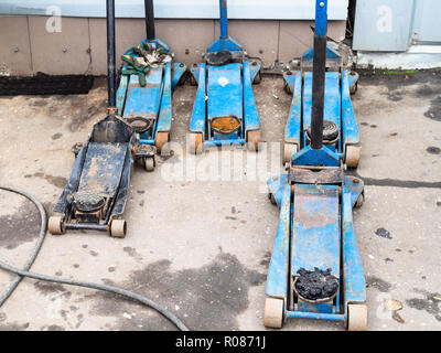 Paar verwendet hydraulische Wagenheber für die Reparatur von Rädern auf im Boden von Auto Service Shop Stockfoto