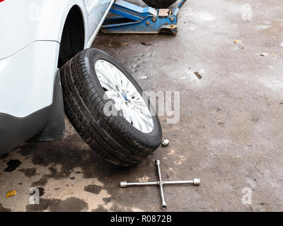 Ausgebaute Rad in der Nähe der angehobenen Fahrzeug im Freien für saisonale Austausch der Reifen Stockfoto