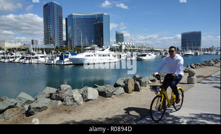 Ein Mann reitet einen gelben Ofo dockless Fahrrad in San Diego Downtown Stockfoto