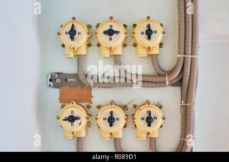 Elektrische Schalter auf einem Weiß verputzte Wand mit angeschlossenen Kabeln. Stockfoto