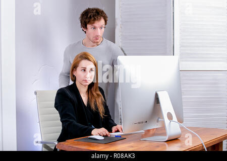 Porträt der jungen erfolgreichen Mann und Frau im Büro. Betrachten Sie die Anzeige in der Überraschung. Schwarzer Freitag oder Cyber Montag. Browsing oder Elemente auswählen, Stockfoto