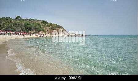 Typisch sardischen Strand (Cala Sinzias) mit kristallklarem Meer und die Vegetation in den Bergen mit Blick auf das Meer. Stockfoto